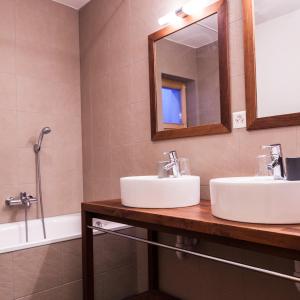 La salle de bains est pourvue de 2 lavabos, d'un miroir et d'une baignoire. dans l'établissement Chalet Magrappe by Swiss Alps Village, à Veysonnaz