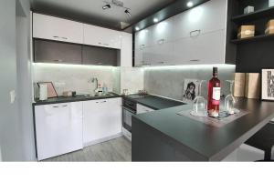 a kitchen with white cabinets and a bottle of wine on a counter at K&K Stylish Elegance in Burgas City