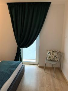 um quarto com uma cama, uma cadeira e uma janela em COZY Nest apartment in Kaunas em Kaunas