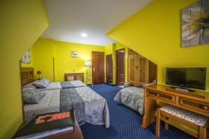 Una habitación de hotel con dos camas y un televisor de pantalla plana. en Alojamiento Calzada Romana, en Belmonte de Miranda
