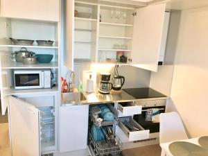 cocina con armarios blancos y microondas en Patria apartments, en Lahti