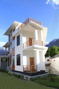 una casa bianca con balcone e montagne sullo sfondo di ISLE OF HIGHLAND TOURS Guest House a Gilgit
