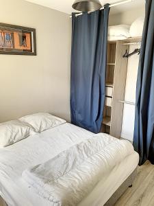 a bed in a room with a blue curtain at 2 PIECES CENTRE ET MER in Cabourg