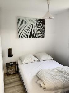 a bed in a bedroom with a painting of a zebra at 2 PIECES JARDIN, ACCES DIRECT MER ET PROCHE THALASSO in Cabourg