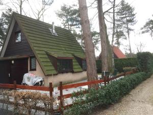 una casa con techo verde y valla en Ferias E55, en Lanaken