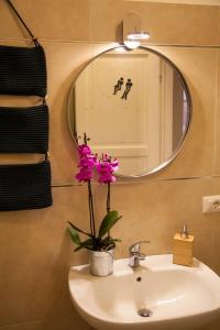 a bathroom with a sink with a mirror and a flower at Naturalmente abitare in Catania