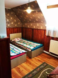 two beds in a room with wooden walls and wooden floors at Motel Hanul Balota in Drobeta-Turnu Severin