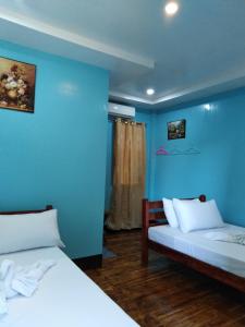 een kamer met 2 bedden en een blauwe muur bij Southside Tourist Inn in Loboc