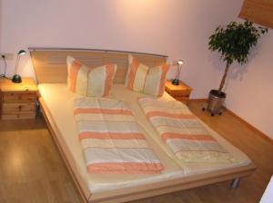 a large bed with striped pillows and a plant at Ferienwohnung Martin Mathies in Sankt Gallenkirch