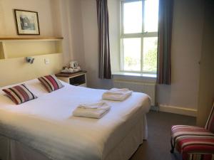 a bedroom with two towels on a bed with a window at The Brotherswater Inn in Patterdale