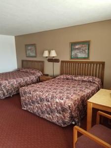 Habitación de hotel con 2 camas y mesa en Raine Motel, en Valentine