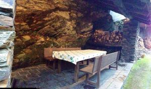 a table and bench in front of a stone wall at Casa Do Concello in Arnado
