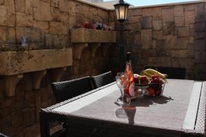 a table with a basket of fruit and a bottle on it at Cosy Home in Mellieħa