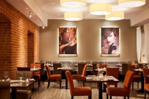a restaurant with tables and chairs and portraits on the wall at Metropolitan Boutique Hotel in Krakow