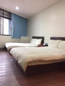 two beds sitting in a room with at Xiang Dou Hotel in Jiaoxi