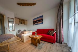 a living room with a red couch and a bed at Ferienwohnungen Haus Erli in Mittenwald