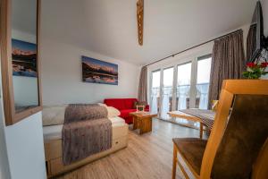 a living room with a couch and a red chair at Ferienwohnungen Haus Erli in Mittenwald