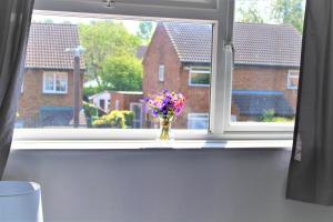 een vaas met bloemen op een vensterbank bij Homely and Budget Friendly 3 bed house Sleeps 6 Free Parking! in Milton Keynes