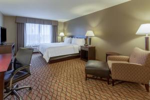a hotel room with a bed and a desk and chairs at Holiday Inn Eau Claire South, an IHG Hotel in Eau Claire