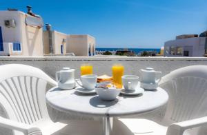 a white table with a bowl of food and orange juice at Join Us Low Cost Rooms in Kamari