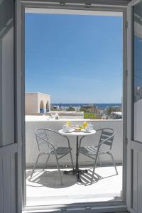 una mesa y sillas en un balcón con vistas en Join Us Low Cost Rooms, en Kamari