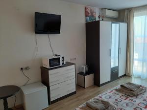 a living room with a dresser with a tv on the wall at Alexander Lozenets Beach Complex Apartment in Lozenets