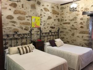 two beds in a room with stone walls at Casa Rural La Antigua Tahona in Candelario