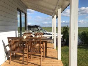 eine Veranda mit einem Tisch, Stühlen und einem Boot in der Unterkunft Baltic Waterfront Yacht House in Świnoujście