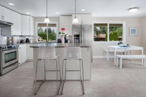 アロアにあるAloha Villaの白いキャビネットとバースツール付きの島のあるキッチンが備わります。