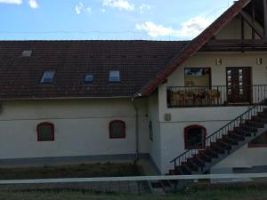 biały budynek z balkonem i schodami w obiekcie Prosper Lovasklub Panzió w mieście Piliscsév