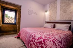 a bedroom with a bed with a red blanket and a window at A Queijaria in Barreira