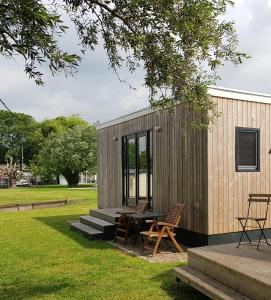 a tiny house with a picnic table and chairs at Tiny House by the water - de Schans Alphen in Alphen