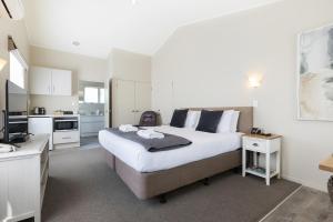 a bedroom with a large bed and a kitchen at Colonial Court Motor Inn in Tauranga