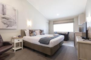 a bedroom with a bed and a living room at Colonial Court Motor Inn in Tauranga