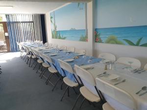 South Seas Motel في ميريمبولا: غرفة مع طاولة طويلة مع كراسي بيضاء وطاولات زرقاء