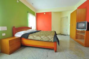 a bedroom with a bed and a flat screen tv at The Casiita Coorg in Kushālnagar