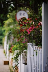 a white picket fence with pink flowers on it at Ancient Street No.5 Youth Chic Hotel in Wuyishan