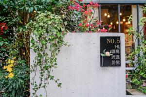 um sinal no lado de uma parede com flores em Ancient Street No.5 Youth Chic Hotel em Wuyishan