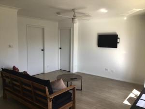 uma sala de estar com um sofá e uma televisão na parede em Ocean View Villas em Vincentia