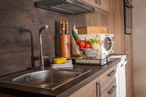 a kitchen counter with a sink with vegetables in a toaster at Haus Edelraute in Mittenwald