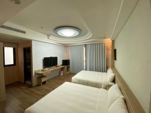 pokój hotelowy z 2 łóżkami i telewizorem w obiekcie 天強民宿 w mieście Magong