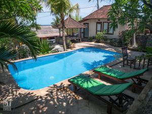 a swimming pool with lounge chairs and a house at Anugerah Villas in Amed