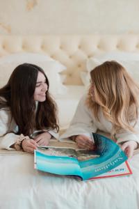 two women laying on a bed reading a book at Castellano Hotel & Suites in Nafplio