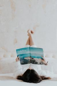 a woman laying on a bed reading a book at Castellano Hotel & Suites in Nafplio