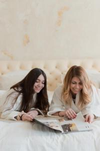 two women laying on a bed reading a magazine at Castellano Hotel & Suites in Nafplio