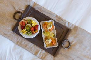 a tray with a plate of food and a plate of fruit at Castellano Hotel & Suites in Nafplio