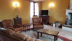 a living room with a couch and chairs and a tv at Maison Charentaise in Les Essards