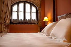 a bedroom with a large bed with a window at Hotel Alcázar de la Reina in Carmona