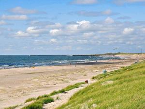 a beach with people on the sand and the ocean at 8 person holiday home in Ringk bing in Ringkøbing