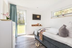 1 dormitorio con cama y ventana en 5 Sterne-Ferienhaus-See-Sauna-Kamin-Garten im Naturpark en Krakow am See